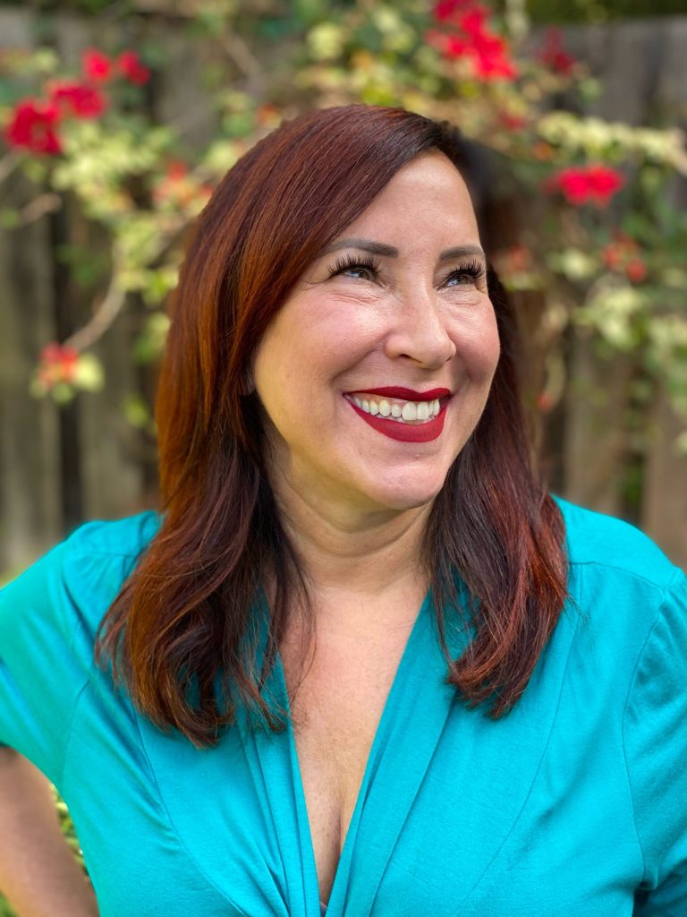 Brunette woman in turquoise shirt smiling.