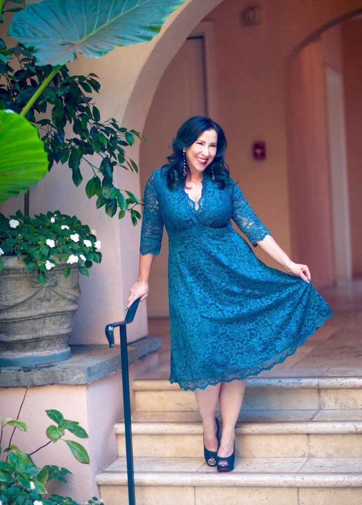 Woman posing for a photo on stairs in a turquoise Kiyonna dress. 