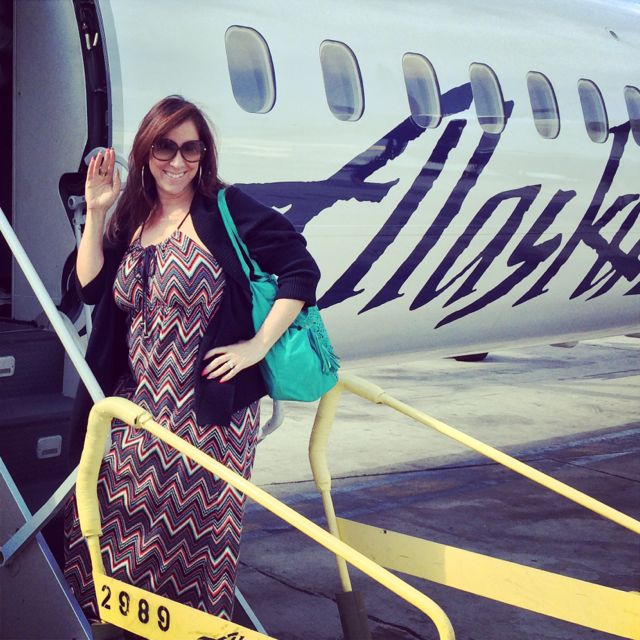 A woman waving outside of an Alaska Airlines plane.